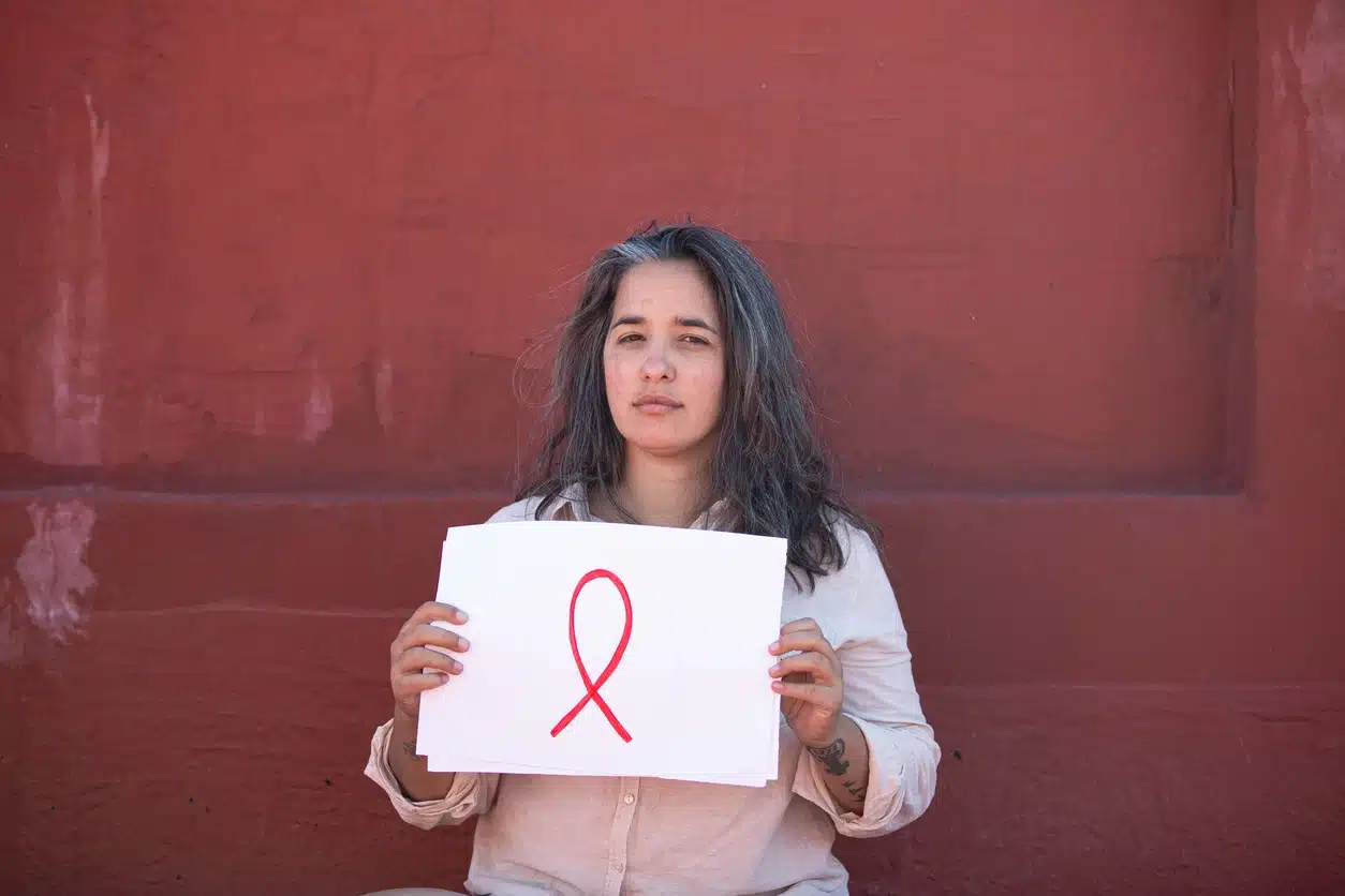 Donna che sostiene un cartello con il simbolo della lotta al tumore